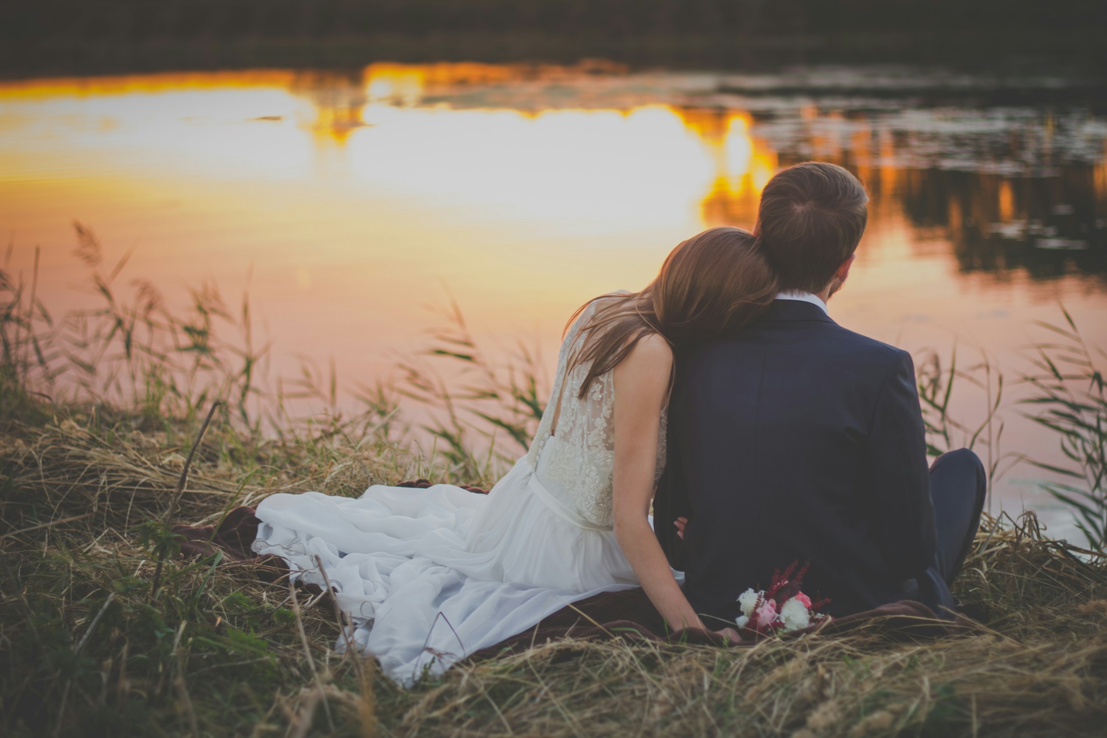 Couple sitting lakeside at sunset