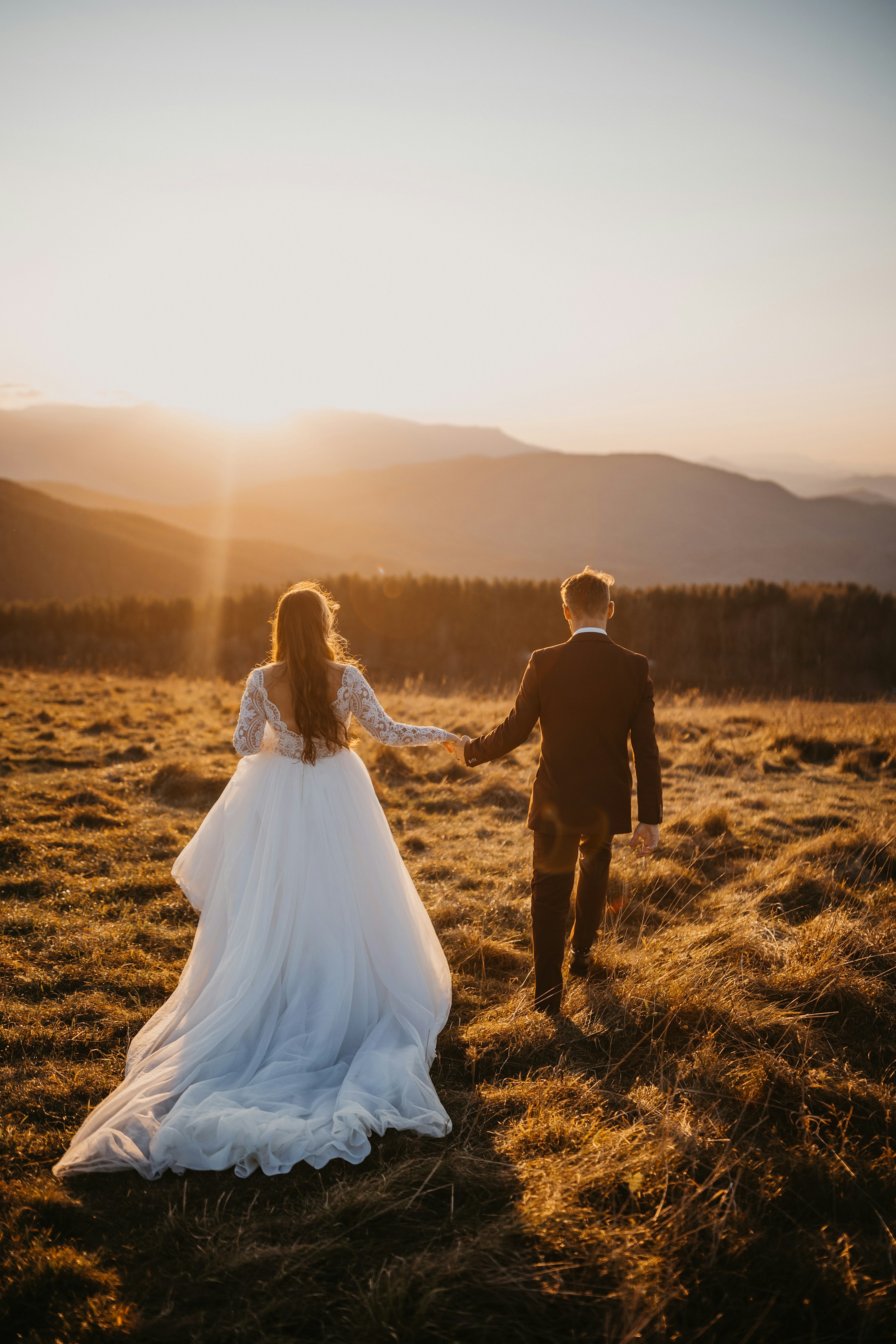 Bride and groom walking through tall grass