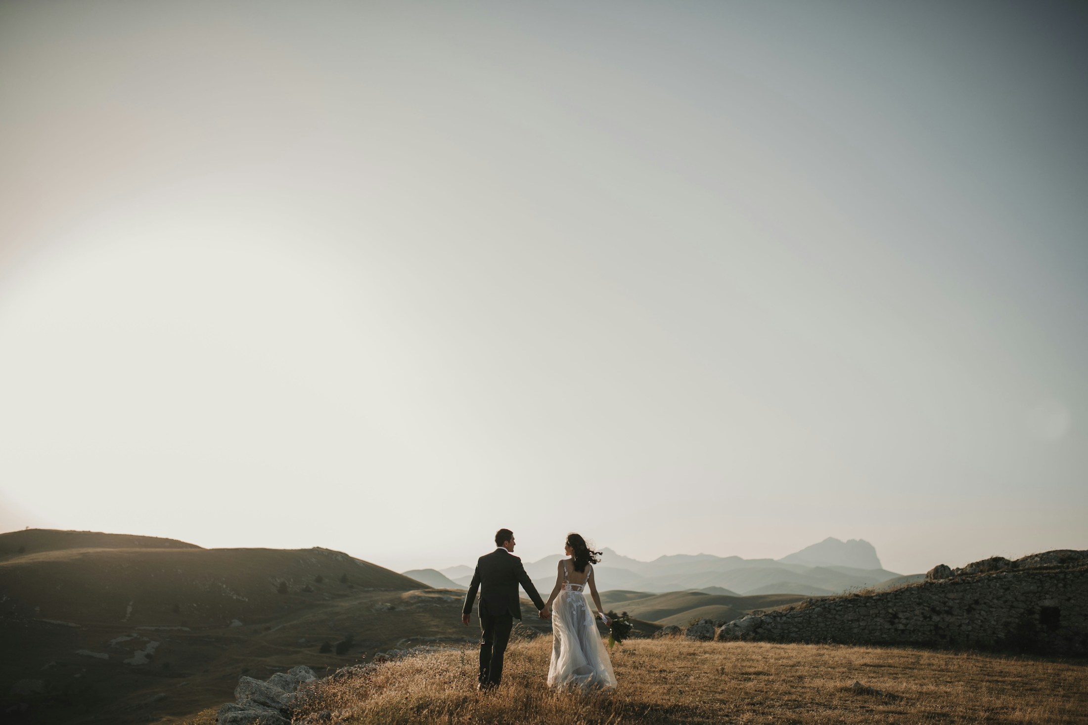 Bride and groom walking through golden hills
